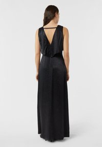 Czarna sukienka do ziemi z głębokim dekoltem na plecach, wykonana z pofałdowanego materiału, z szerokimi ramiączkami i prostym krojem.