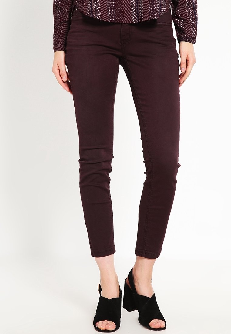 Vínové úzké d�žíny s přiléhavým střihem a hladkou texturou, doplněné černými sandály s otevřenou špičkou na podpatku s robustním podpatkem.