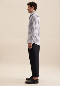 Blauw-witte geblokte overhemd met lange mouwen, slim fit, gecombineerd met donkere broek en zwarte schoenen. Gladde katoenen stof, button-down kraag.