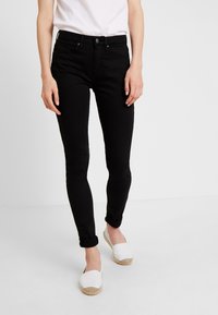Mustad mustad teksad keskmise tõusuga, viie taskuga ja klassikalise nupuklõpsuga. Kandmisel valged espadrillid.