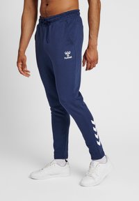 Mörkblå joggers i en smal passform, med en elastisk midja, sidostrecker och en logotyp på låret. Slät bomullsblandning.