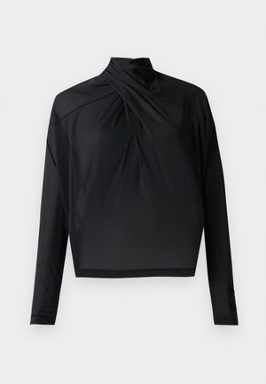 Mustast pikkade varrukate ja kõrge kaelusega topp, millel on keeratud esidetail. Valmistatud siledast kangast, lühendatud pikkusega ja kokkuhoitavate varrukatega.