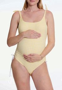 Svangerskapsbadetøy i gult rutete mønster med justerbare skulderbånd og sidesnorer. Glatt tekstur med en tettsittende design.