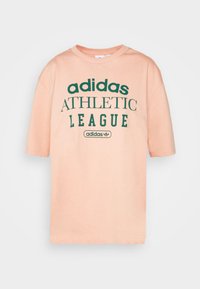 Šviesiai rožinė medvilninė marškinė su trumpomis rankovėmis, ant kurių yra žaliai spausdinta užrašas "adidas ATHLETIC LEAGUE" ir mažas Adidas logotipo akcentas.