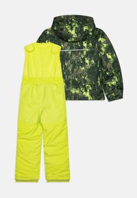 Giacca invernale verde e gialla con motivo mimetico e pantaloni salopette abbinati. La giacca è dotata di un cappuccio e di dettagli riflettenti.