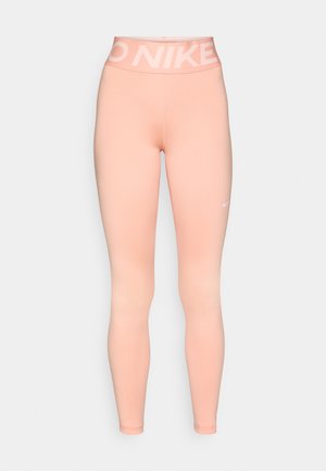 Pink Nike leggings feature a high waistband with a white logo. The fabric is smooth with a fitted silhouette, suitable for active wear.