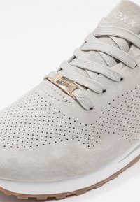 Baskets en suède gris clair avec des détails perforés, des lacets plats, un accent en métal doré et une semelle blanche. Conception à bout rond.