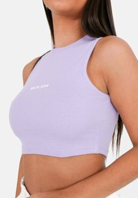 Fialový žebrovaný crop top s límečkem. Na přední straně je bílý logo "SIXTH JUNE". Bezrukávový design s těsným střihem.