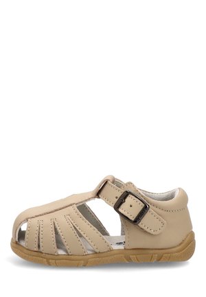 Sandalia beige para niño pequeño con puntera cerrada, cortes laterales, correa ajustable con hebilla y suela de goma marrón texturizada.