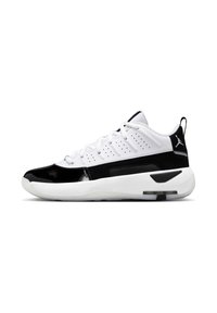 Hvide og sorte low-top atletiske sneakers med snørebånd, perforeret overdel, tyk sål og Air Jordan-logo på hælflappen, set fra siden.