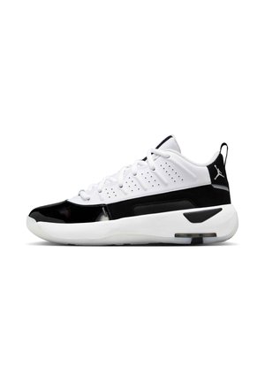 Hvide og sorte low-top atletiske sneakers med snørebånd, perforeret overdel, tyk sål og Air Jordan-logo på hælflappen, set fra siden.