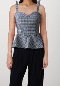 Top peplum en cuadros vichy azul marino y blanco, con tirantes ajustables y escote en forma de corazón. Tela suave y tejida con una forma estructurada.