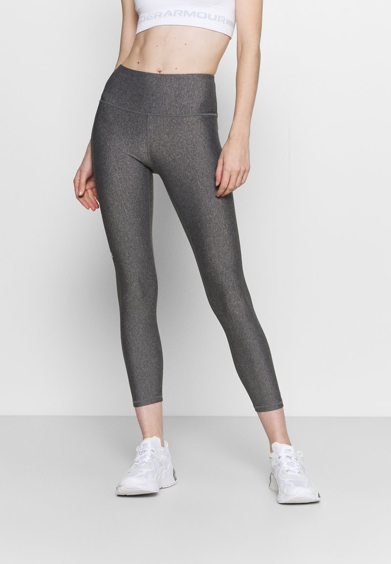 Grå, högmidjade leggings med en slät, texturerad yta, med en figurnära passform och ankellång fåll. I kombination med vita träningsskor.
