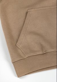 Kreemika värvi dressipluusi ääre, ees tasku, soonikkoes varrukad ja sile tekstuur. Õmblused ja allõmblused on nähtavad.