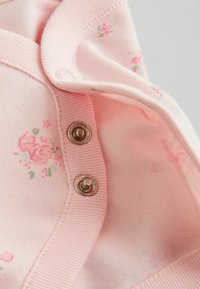 Hele roosa puuvillane riideese väikeste lillemustritega. Omab hõbedasi trukknappe ja soonikkoes servasid. Pehme tekstuur kerge läikega.