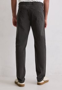 Ciemnoszare, lekkie spodnie o prostym kroju nogawek, z dwoma tylnymi kieszeniami i gładką fakturą. Do tego beżowe sneakersy.