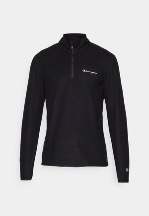 Musta neljännesvetoketjulli pullover pitkähihaisilla, pehmeää kangasta, jossa on pieni valkoinen logo vasemmassa rinnassa ja hihansuissa yksityiskohtia.