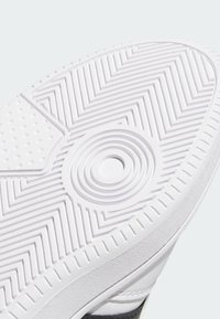 White sneaker sole with circular and zigzag tread patterns designed for grip and traction.