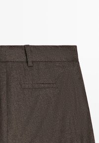 Pantalon en laine brun montrant la ceinture avec boucle de ceinture et une seule poche passepoilée arrière sur le côté droit.