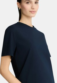 T-shirt a maniche corte di colore blu navy, realizzato in un tessuto liscio, con scollatura rotonda e vestibilità comoda, privo di modelli o decorazioni visibili.