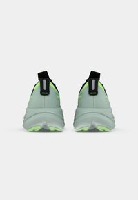 Scarpe da atletica verde chiaro con accenti neri, tomaia in mesh testurizzato e suola prominente ammortizzata con dettagli verde brillante.