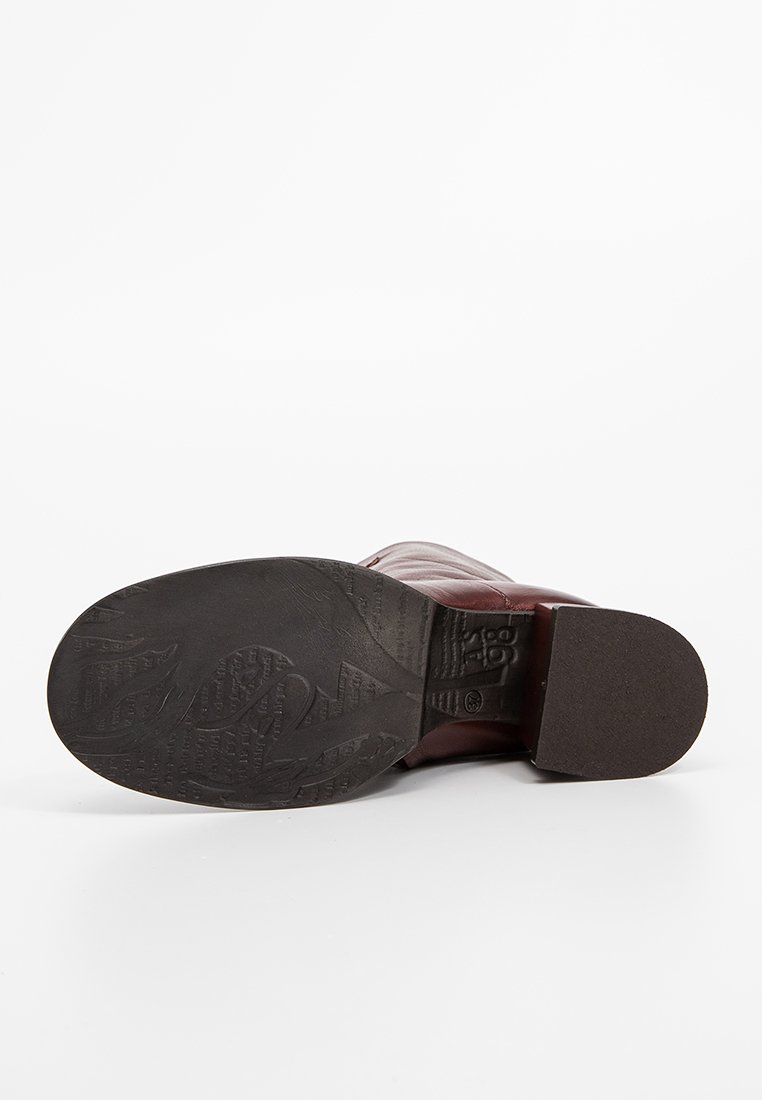 Botín de cuero burdeos con punta redonda, suela de goma texturizada y un sutil detalle de costura. Tacón plano para mayor estabilidad.