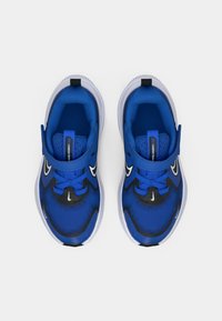 Kék sportcipők hálós anyagból, kerek orral, fekete részletekkel és fehér talppal. Jellemzője a párnázott nyelv és a fűzőrendszer.