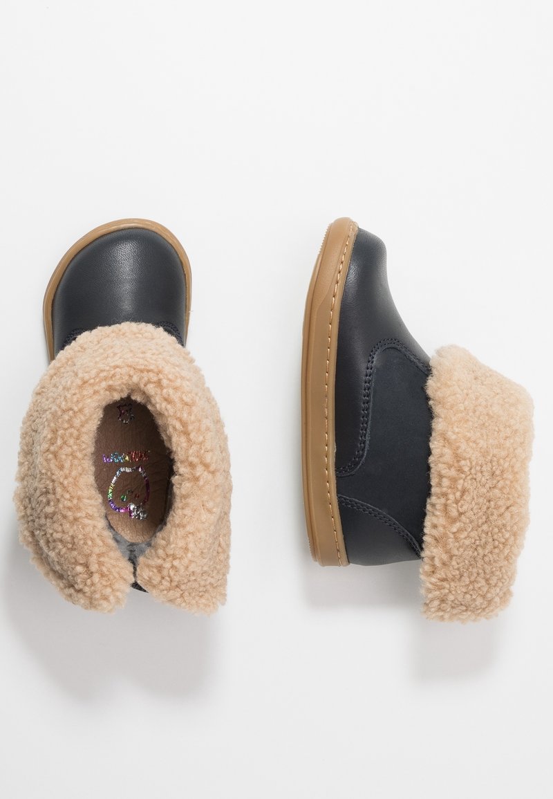 Bottes mi-mollet en cuir noir avec col en fausse fourrure beige, semelles en caoutchouc et semelle intérieure rembourrée. Présentent une couture simple le long des bords.