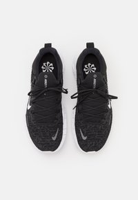 Czarne buty sportowe z teksturowaną cholewką, płaskimi sznurowadłami i białą podeszwą. Na boku znajduje się logo Nike, a na wkładce wzór kwiatowy.