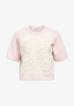 Vaaleanpunainen lyhythihainen neule, jossa on etupuolella teksturoitu kerma-valkoinen kukkakuvio sekä resorit kauluksessa, hihojen helmassa ja helmassa.