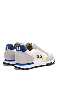 Sneaker con tomaia in pelle bianca, dettagli in suede grigio, linguetta blu sul tallone e suola in gomma nera; presenta loghi sui lati esterni e sul tallone.