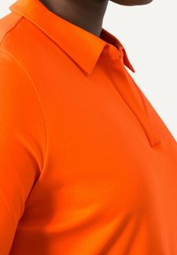 Orange polo tröja med krage och korta ärmar, med en slät yta och subtila söm detaljer nära kragen.