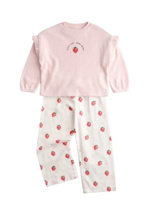 Różowa koszulka z długim rękawem z falbankami na rękawach i haftem truskawek, w zestawie z białymi spodniami pokrytymi czerwonymi nadrukami truskawek.