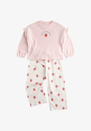 Maglietta rosa a maniche lunghe con maniche a volant e ricamo di fragole, abbinata a pantaloni bianchi decorati con stampe di fragole rosse.