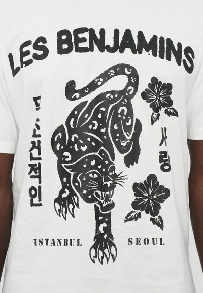T-shirt blanc avec un graphisme noir d'un léopard et de fleurs, accompagné du texte "LES BENJAMINS", "ISTANBUL" et "SEOUL" en dessous.