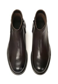 Botas de tobillo de cuero marrón con un acabado suave, punta redondeada y cremallera lateral. Presentan un sutil detalle de costura a lo largo de la suela.