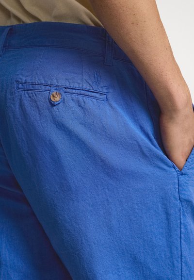 Μπλε λινό παντελόνι με λεία υφή, με πίσω τσέπη που κλείνει με κουμπί και καλοραμμένες λεπτομέρειες.