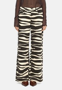 Spodnie szerokie z czarno-kremowym wzorem w zebry, wykonane z denimu. Zawierają kieszenie z przodu oraz metalowe akcenty.