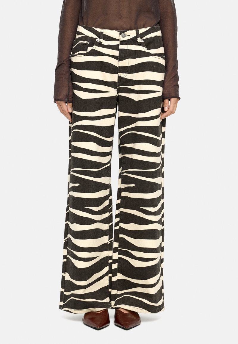 Spodnie szerokie z czarno-kremowym wzorem w zebry, wykonane z denimu. Zawierają kieszenie z przodu oraz metalowe akcenty.