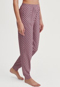 Lichte, roze pyjamabroek met een patroon van zwarte diamanten, elastische tailleband en tapered leg ontwerp. Zachte stoftextuur.