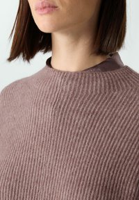 Prążkowany, fioletowawy sweter z wysokim kołnierzem, charakteryzujący się miękką teksturą i dopasowanym krojem; zbliżenie na linię szyi i kołnierz.