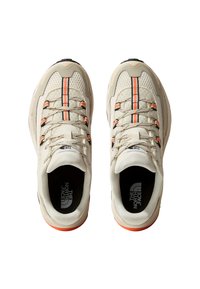 Zapatillas deportivas beige con parte superior de malla, acentos en naranja y negro, suela acolchada y marca interior en negro.