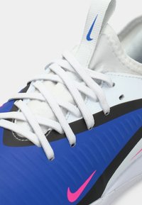 Γαλάζιο και λευκό αθλητικό παπούτσι με υφή στο επάνω μέρος, λευκές κορδόνες και ροζ λογότυπο Nike στο πλάι. Διαθέτει κομψό, χαμηλού προφίλ σχέδιο.