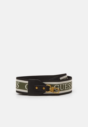 Ceinture en tissu rayée vert et blanc avec extrémités en cuir noir et boucle métallique dorée, portant le nom de la marque GUESS en lettres blanches.