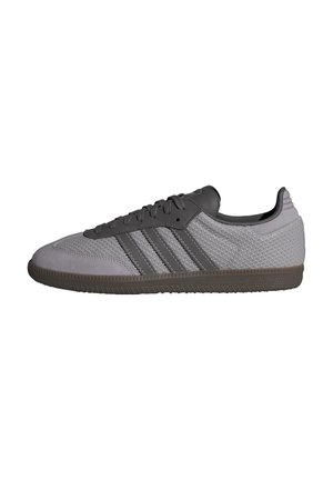 Grå atletisk sko med struktureret mesh-overdel, mørkegrå læderdetaljer, tre striber og gummisål. Klassisk lavprofil design.