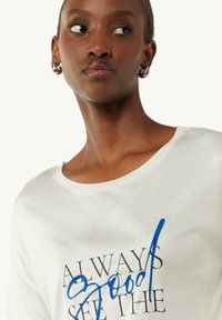 White cotton t-shirt featuring a round neckline and short sleeves, with blue and black text graphics on the front. Smooth texture.