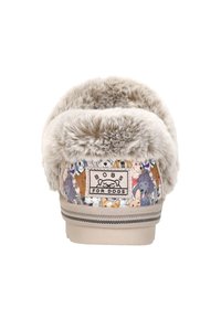 Vrouwelijke instappers met een voering van nepbont, featuring een meerkleurig hondenpatroon, beige basis en zwart-wit gestreepte accenten bij de zool.