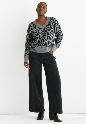 Gray v-neck sweater with black leopard print, ribbed cuffs, and hem. Paired with black wide-leg jeans and black heeled boots.