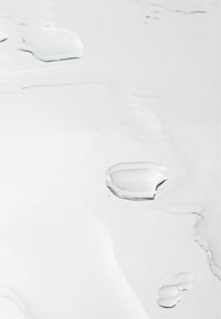 Klart vattendroppar på en slät, reflekterande vit yta. Texturen är blank med en subtil glans, som visar organiska former och mönster.