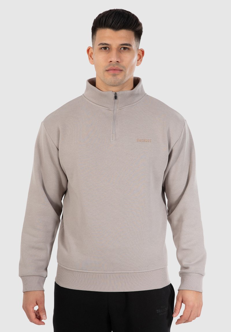 Lichtgrijze zip-up sweatshirt met hoge kraag, geribde mouwen en zoom. Heeft een klein logo op de linkerkant van de borst. Zachte gebreide textuur.